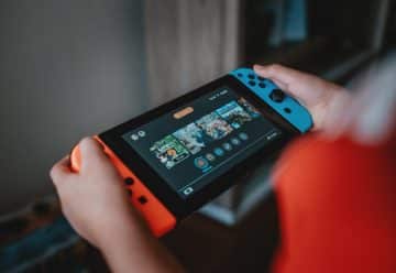 person holding black and orange nintendo switch