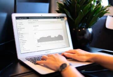 person using macbook air on brown wooden table